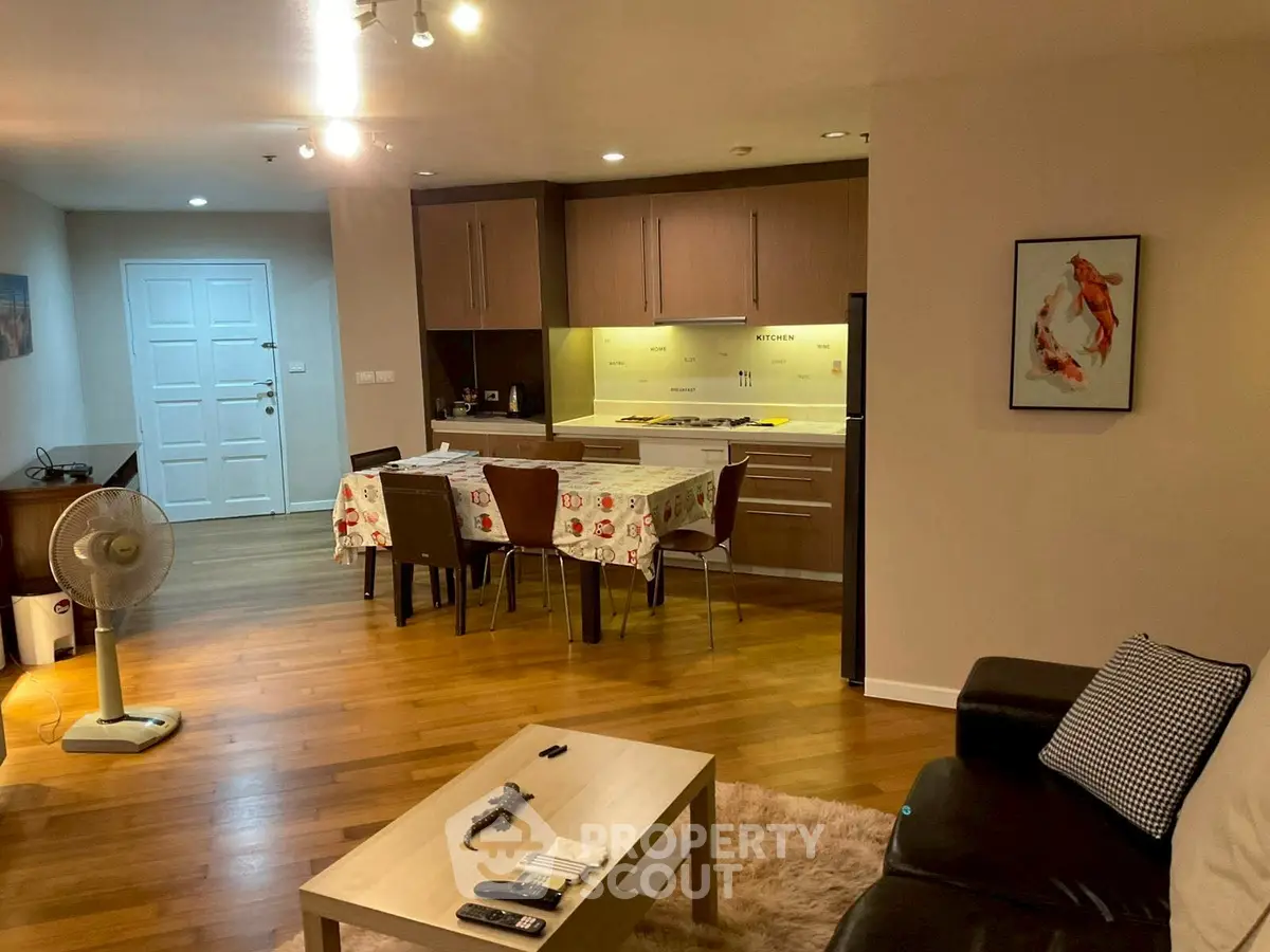 Spacious open-plan living room with modern kitchen and dining area, featuring wooden flooring and cozy furnishings.