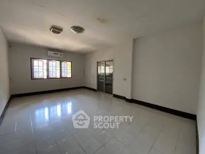 Spacious empty room with tiled flooring and large windows, perfect for customization.