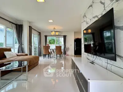 Spacious modern living room with elegant decor and large TV, perfect for family gatherings.