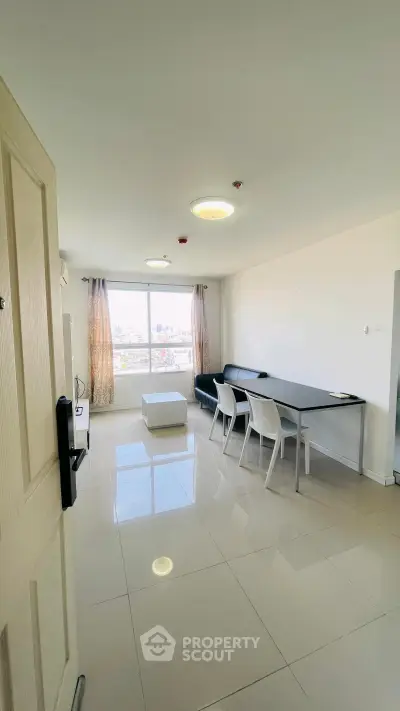 Spacious modern living room with sleek furniture and large window offering city views.