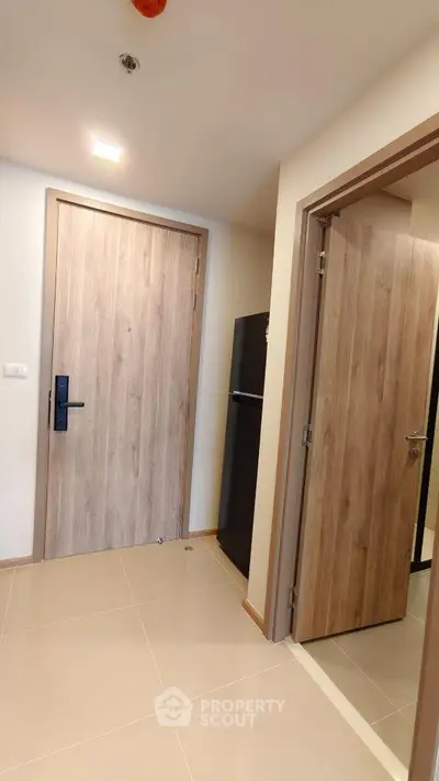 Modern apartment entrance with sleek wooden doors and glossy tiled flooring.