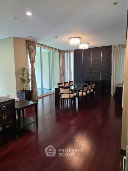 Elegant dining area with hardwood floors and modern lighting in a spacious apartment.