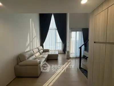 Spacious modern living room with high ceilings and elegant floor-to-ceiling windows.