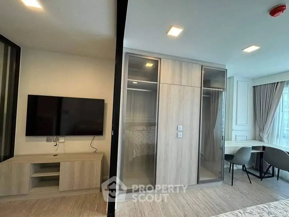 Modern living room with wall-mounted TV and stylish furniture in a bright apartment.