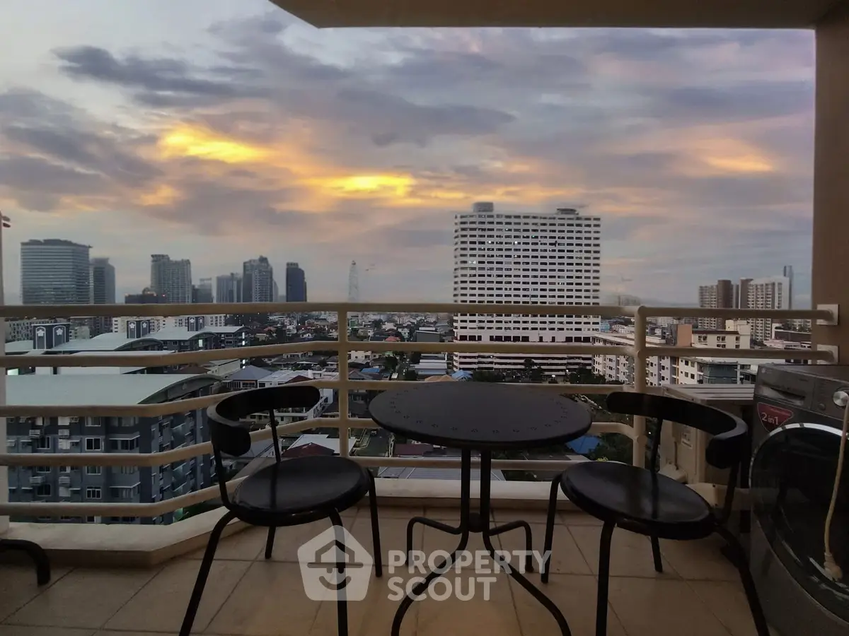 Stunning city view from a high-rise balcony with modern seating at sunset.