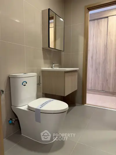 Modern bathroom with sleek fixtures and neutral tones, featuring a wall-mounted vanity and mirror.