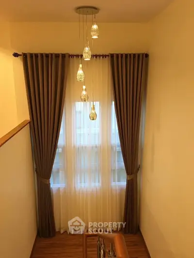 Elegant staircase with modern lighting and floor-to-ceiling curtains in a cozy home interior.