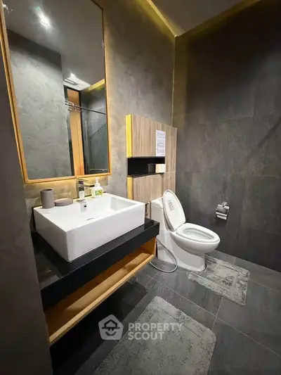 Modern bathroom with sleek design, featuring a stylish sink and toilet in a contemporary setting.