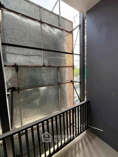 Small balcony with metal railing and industrial backdrop