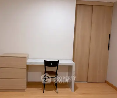 Minimalist study area with wooden desk, chair, and storage cabinet in modern apartment.