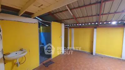 Spacious unfinished interior with bright yellow walls and exposed ceiling.