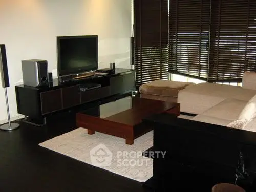 Modern living room with sleek furniture and entertainment center, featuring a cozy sectional sofa and stylish decor.