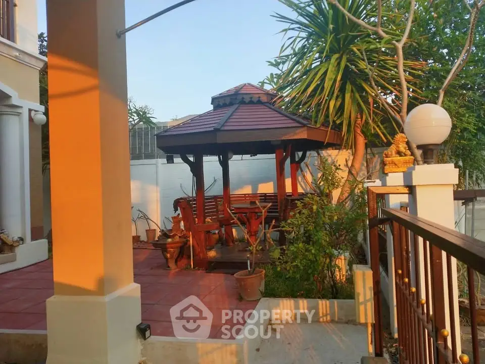 Charming garden gazebo with wooden seating in a serene backyard setting.