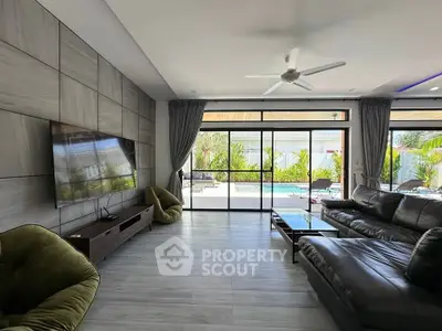 Spacious modern living room with pool view, sleek furniture, and large windows for natural light.