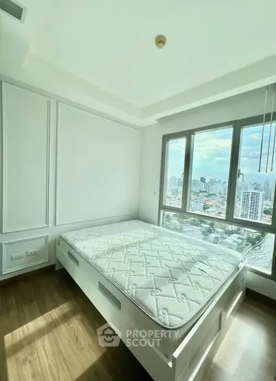 Bright bedroom with large window offering stunning city views, featuring a comfortable bed and modern design.