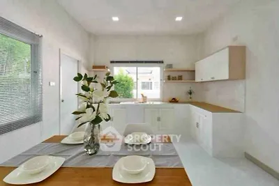 Modern kitchen with open layout and elegant dining setup, featuring white cabinetry and natural light.