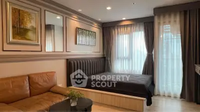 Modern bedroom with elegant decor and natural light, featuring a cozy bed and stylish sofa.