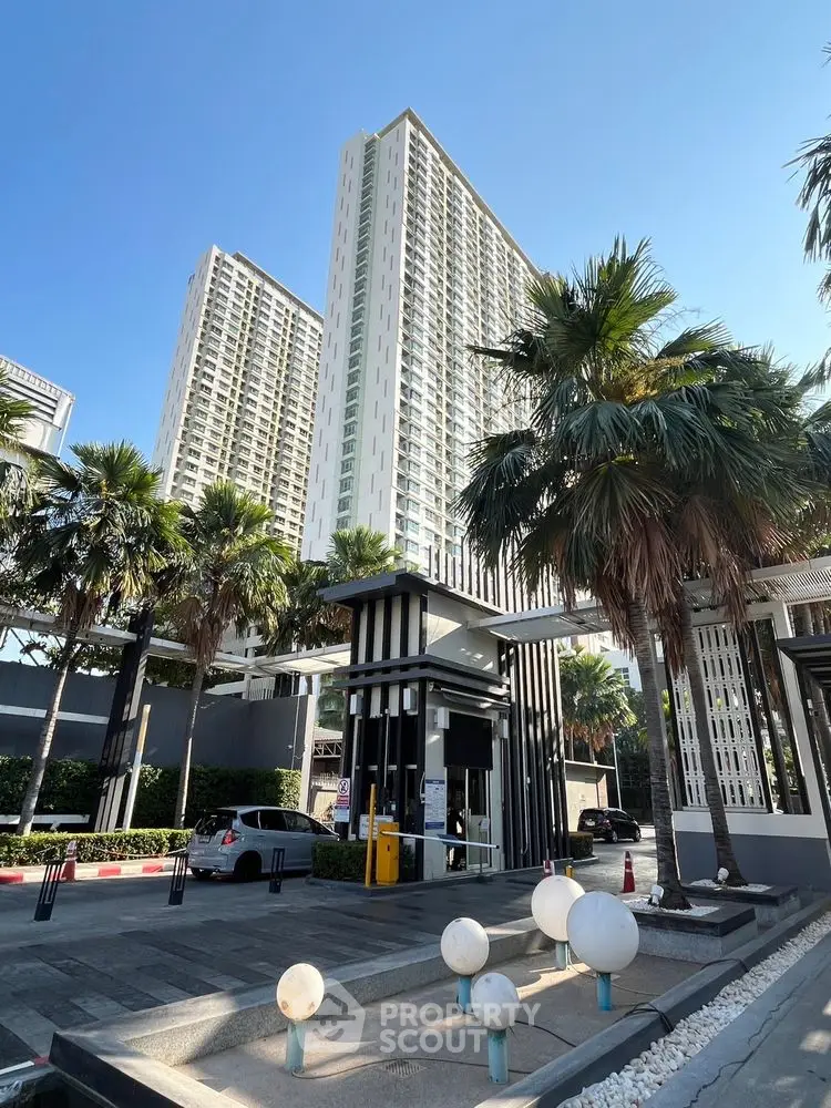 Stunning high-rise building with modern entrance and lush palm trees.