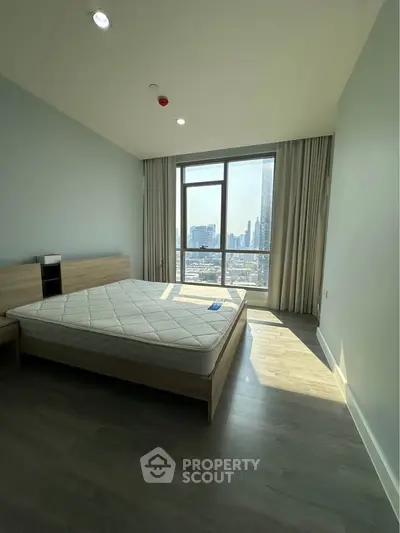 Spacious bedroom with large window offering stunning city view, modern design and ample natural light.