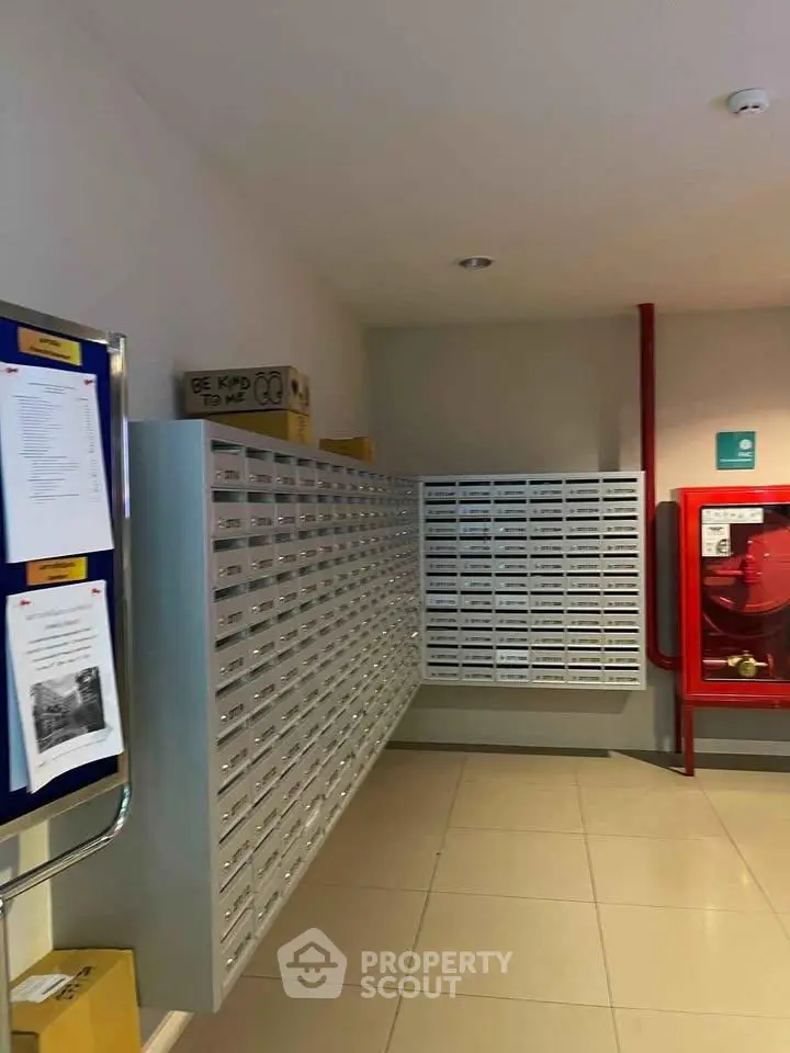 Modern apartment building mailroom with organized mailboxes and fire safety equipment.