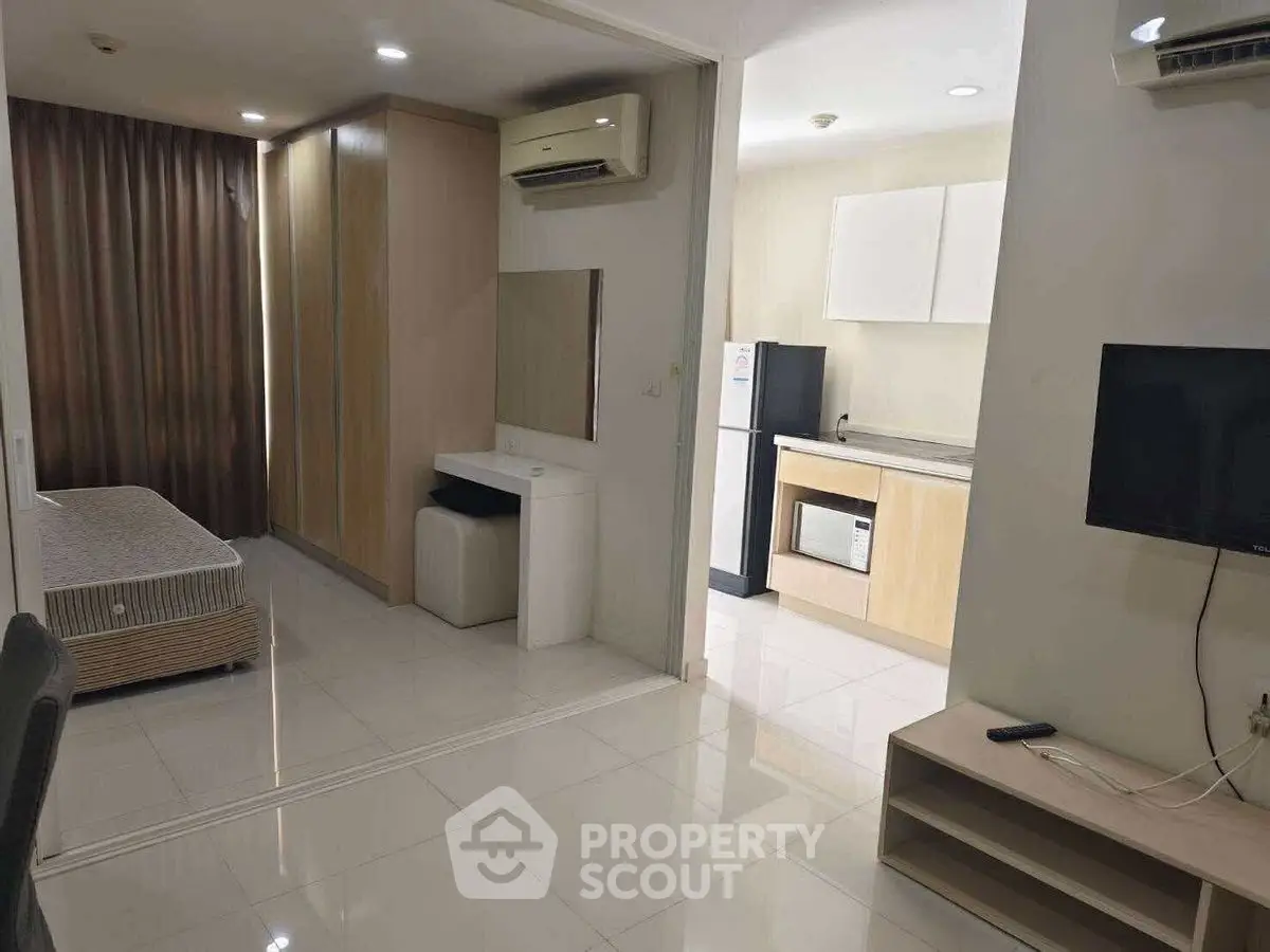 Modern studio apartment with open layout and sleek kitchen appliances.