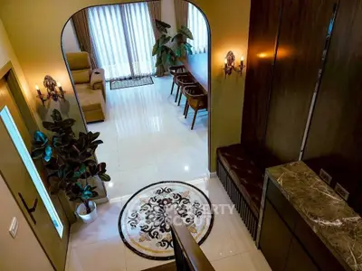 Elegant living room with modern decor and large dining table, featuring stylish lighting and polished floors.