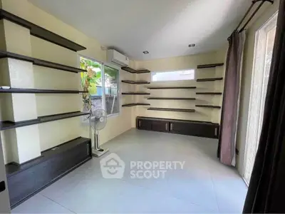 Spacious room with modern shelving and natural light, perfect for a home office or study area.