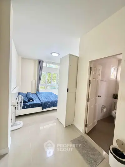 Modern bedroom with ensuite bathroom and large window offering natural light.