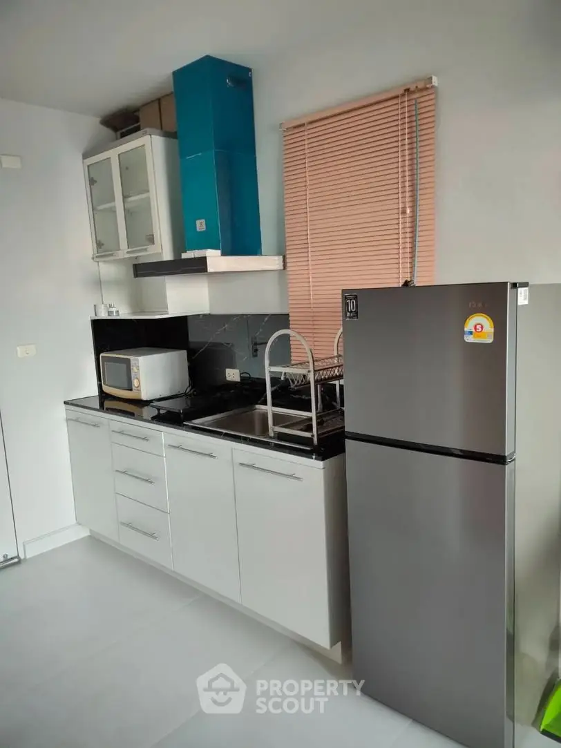 Modern kitchen with sleek cabinets, stainless steel fridge, and microwave, perfect for urban living.