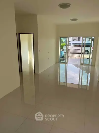 Spacious living room with glossy tiled floors and large windows leading to a balcony.