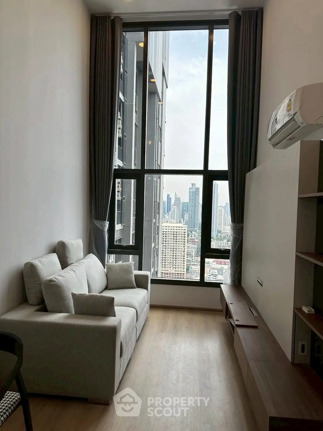 Modern living room with city view, featuring sleek furniture and large windows for natural light.
