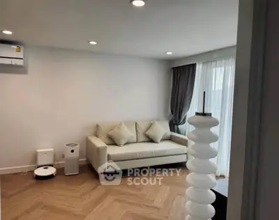 Modern living room with stylish sofa and elegant lighting, featuring hardwood floors and natural light.