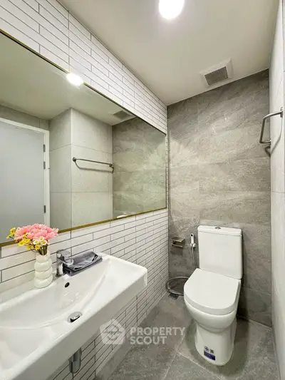 Modern bathroom with sleek design, featuring a large mirror, elegant sink, and stylish tiles.