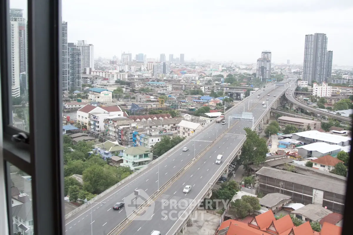 Stunning cityscape view from high-rise window overlooking urban skyline and highway.