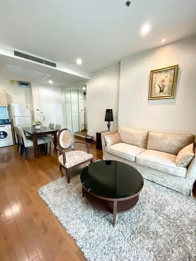 Elegant living room with plush sofa, stylish armchair, and modern dining area in open layout apartment.