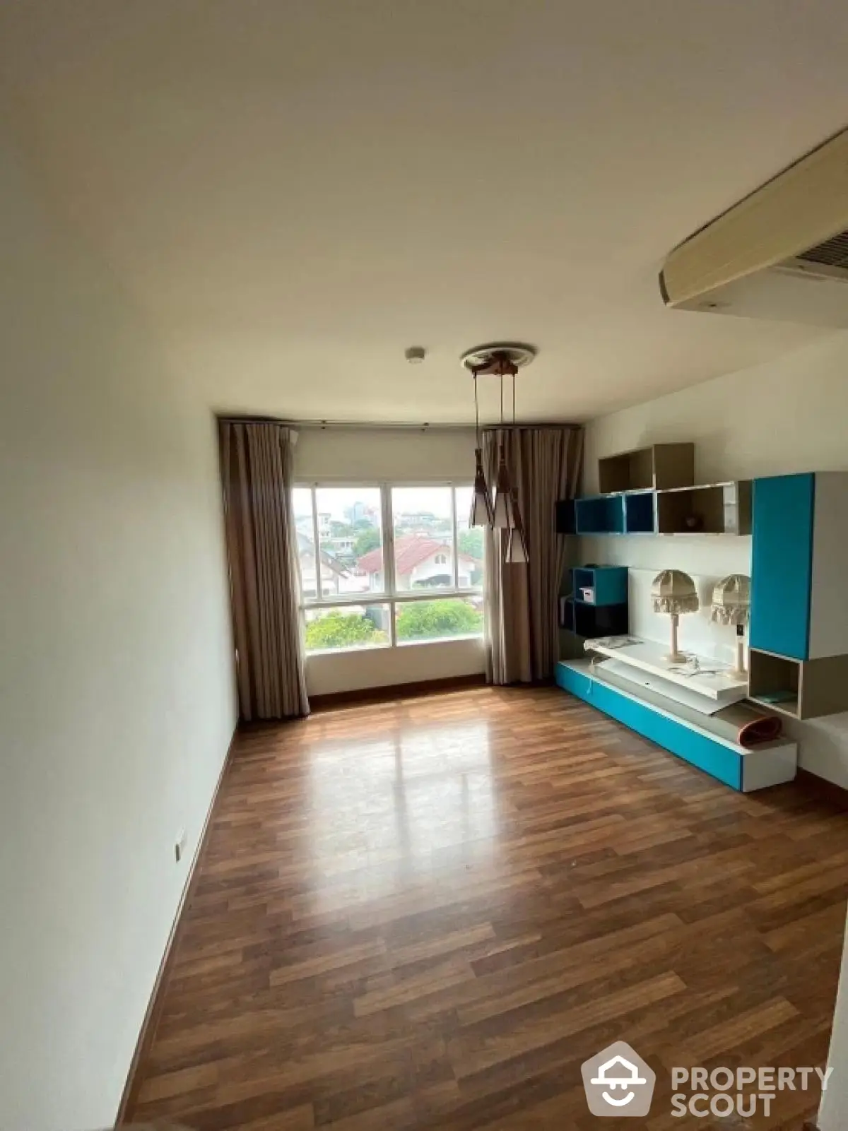 Spacious unfurnished room with large window and wooden flooring, ideal for customization.