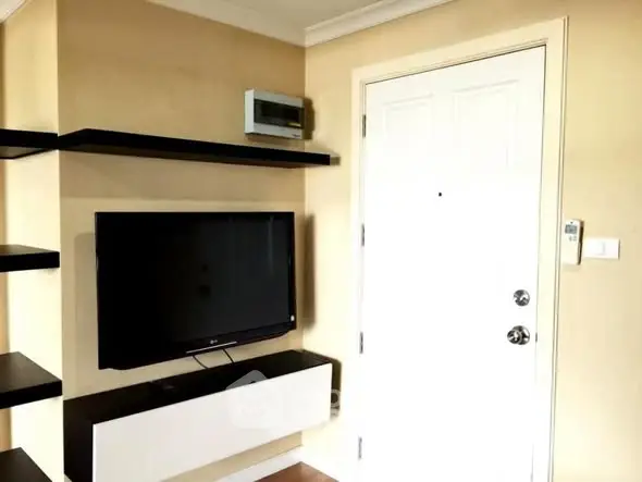 Modern living room corner with wall-mounted TV and sleek shelving.