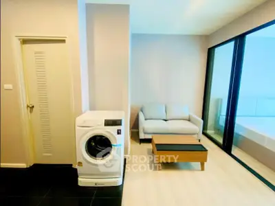 Modern living room with washing machine and cozy sofa near large windows.