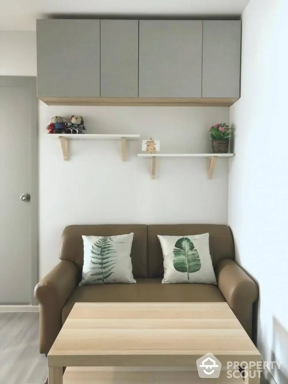 Cozy living room with brown sofa and decorative pillows, wooden coffee table, and wall shelves.