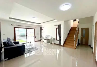 Spacious modern living room with sleek staircase and large windows for natural light.