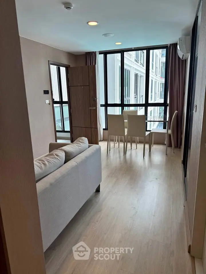 Modern living room with large windows and dining area in a stylish apartment.