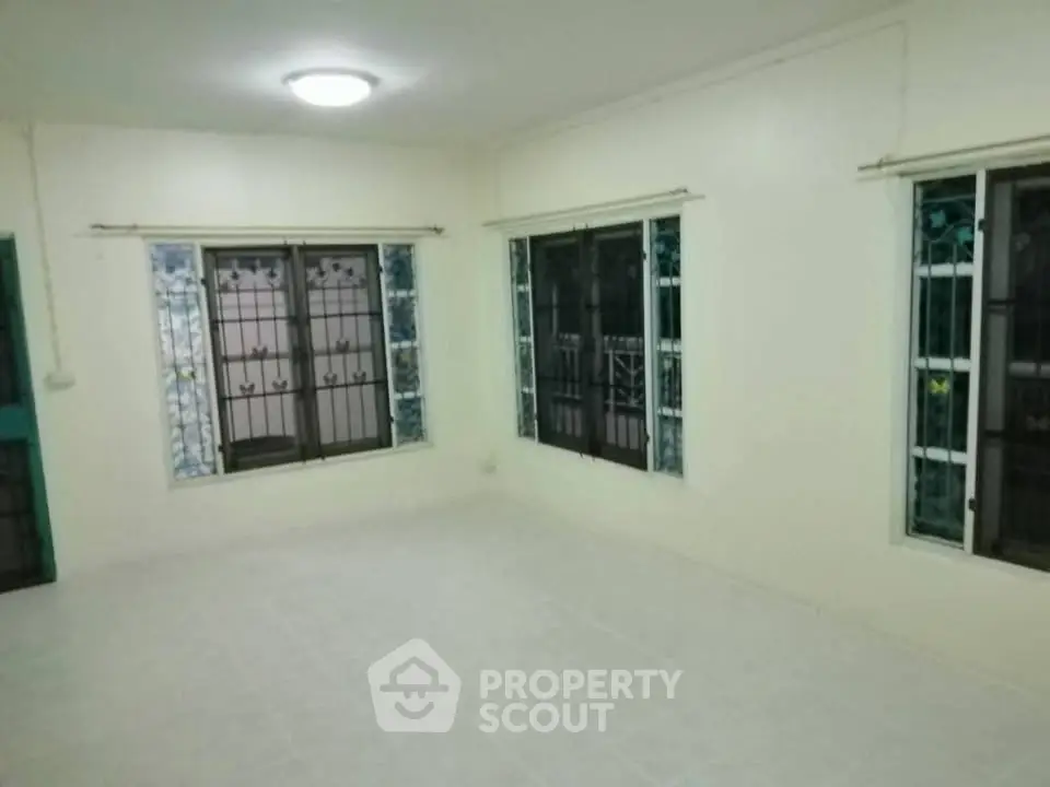 Spacious empty room with tiled floor and large windows, ideal for customization.