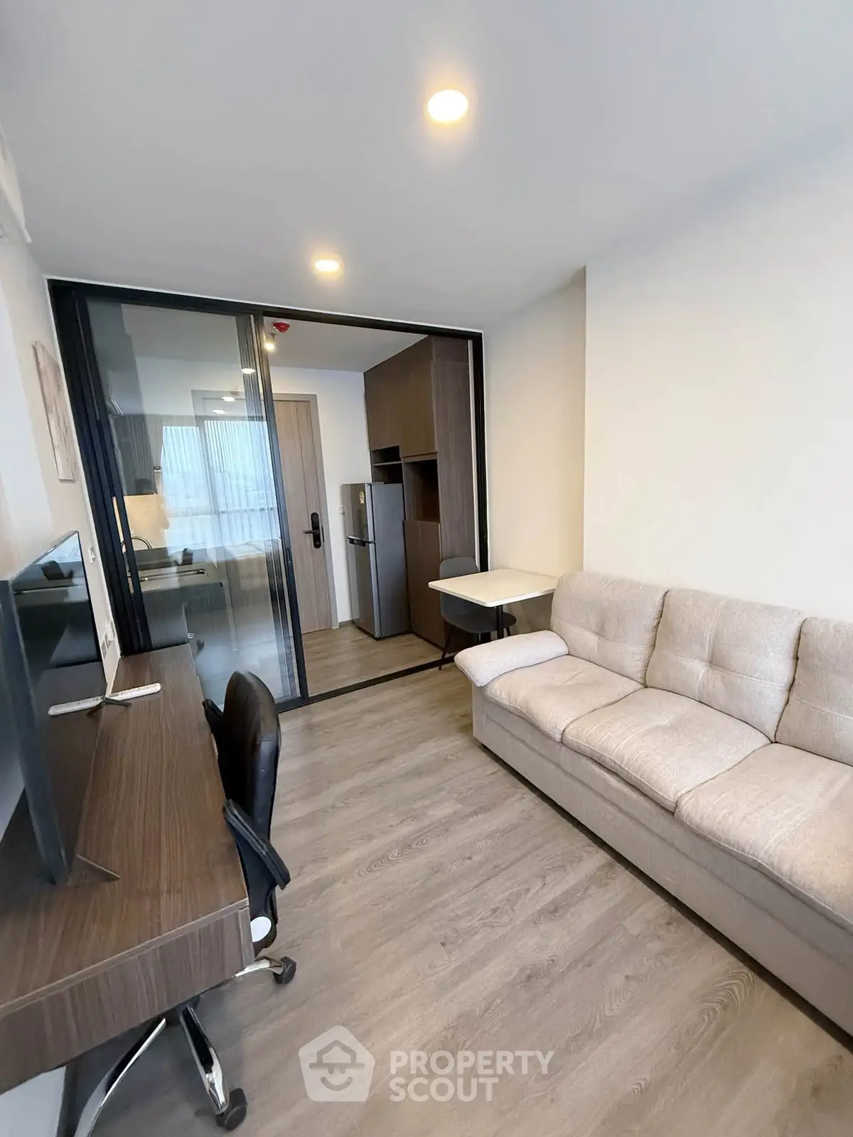 Modern living room with sleek furniture and sliding glass doors leading to a compact kitchen area.