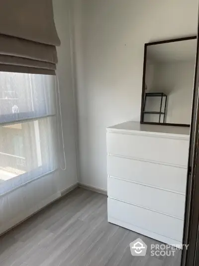 Bright minimalist bedroom with white dresser and large window