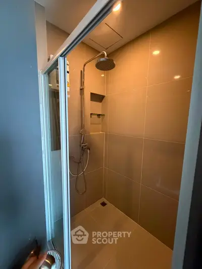 Modern shower area with sleek tile design and rainfall showerhead in a contemporary bathroom.