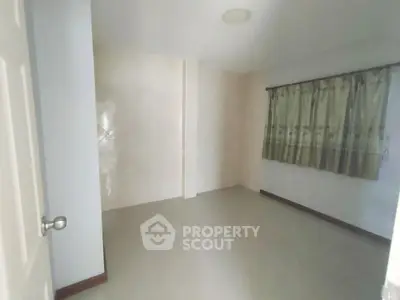 Spacious empty room with tiled floor and window, ideal for customization.