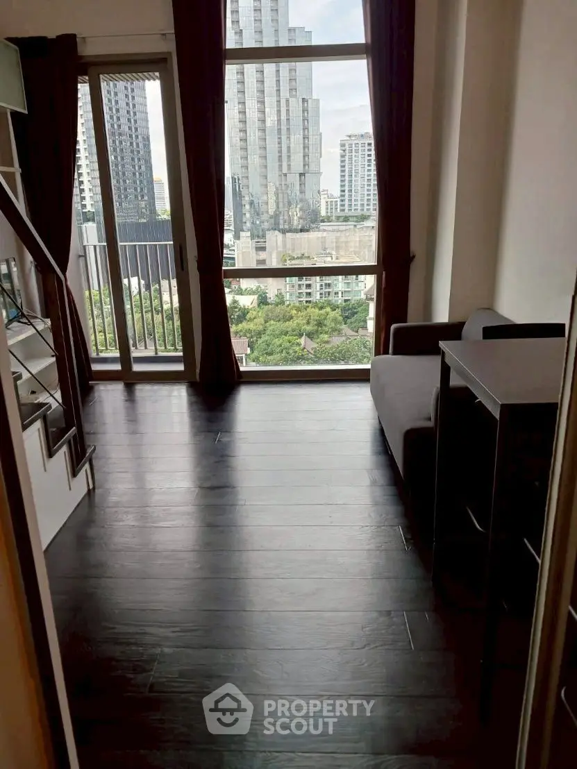 Modern high-rise apartment with stunning city view and dark wood flooring.