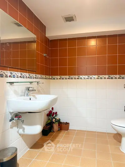 Charming bathroom with warm tiles and modern fixtures, perfect for a cozy home.