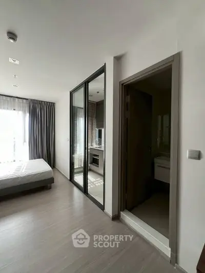 Modern bedroom with large windows and en-suite bathroom in a stylish apartment.