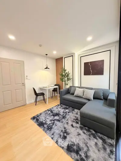 Modern living room with stylish gray sofa and dining area in open layout apartment.